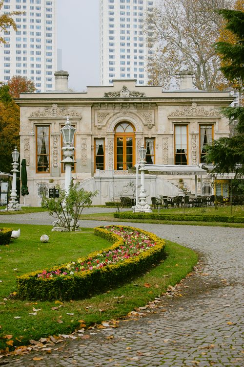 Free Elegant historical building amidst urban park with manicured gardens and pathway. Stock Photo