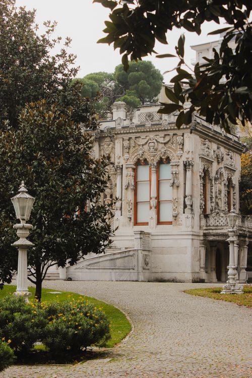 Free A beautifully decorated historic building surrounded by lush greenery and elegant pathways. Stock Photo