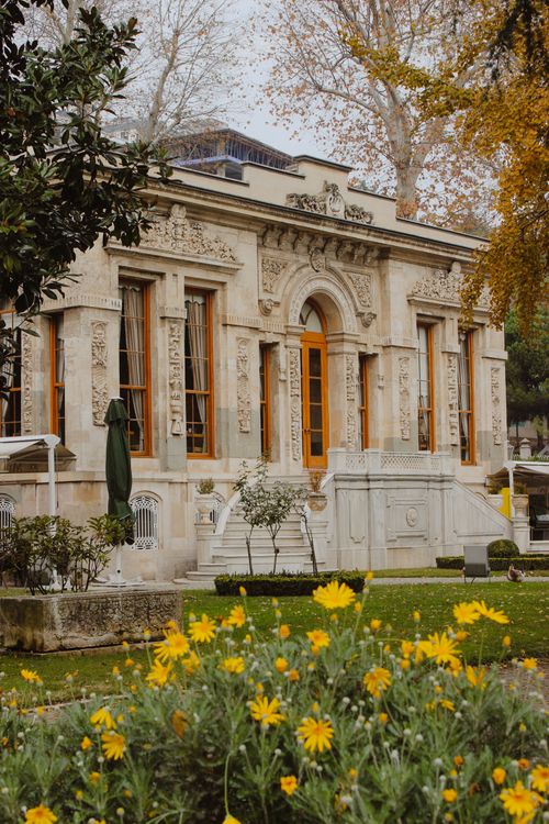 Free Charming historic building with ornate details surrounded by vibrant garden in fall. Stock Photo