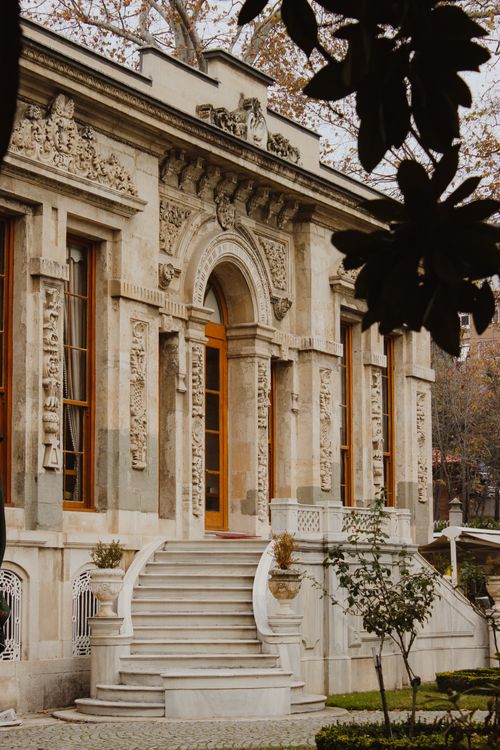 Free Beautiful historic building with ornate carvings and grand steps, set in a serene garden. Stock Photo