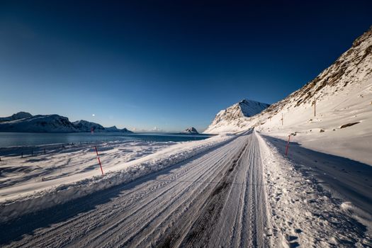 Breathtaking view of a snowy road under clear blue skies, showcasing Arctic beauty.