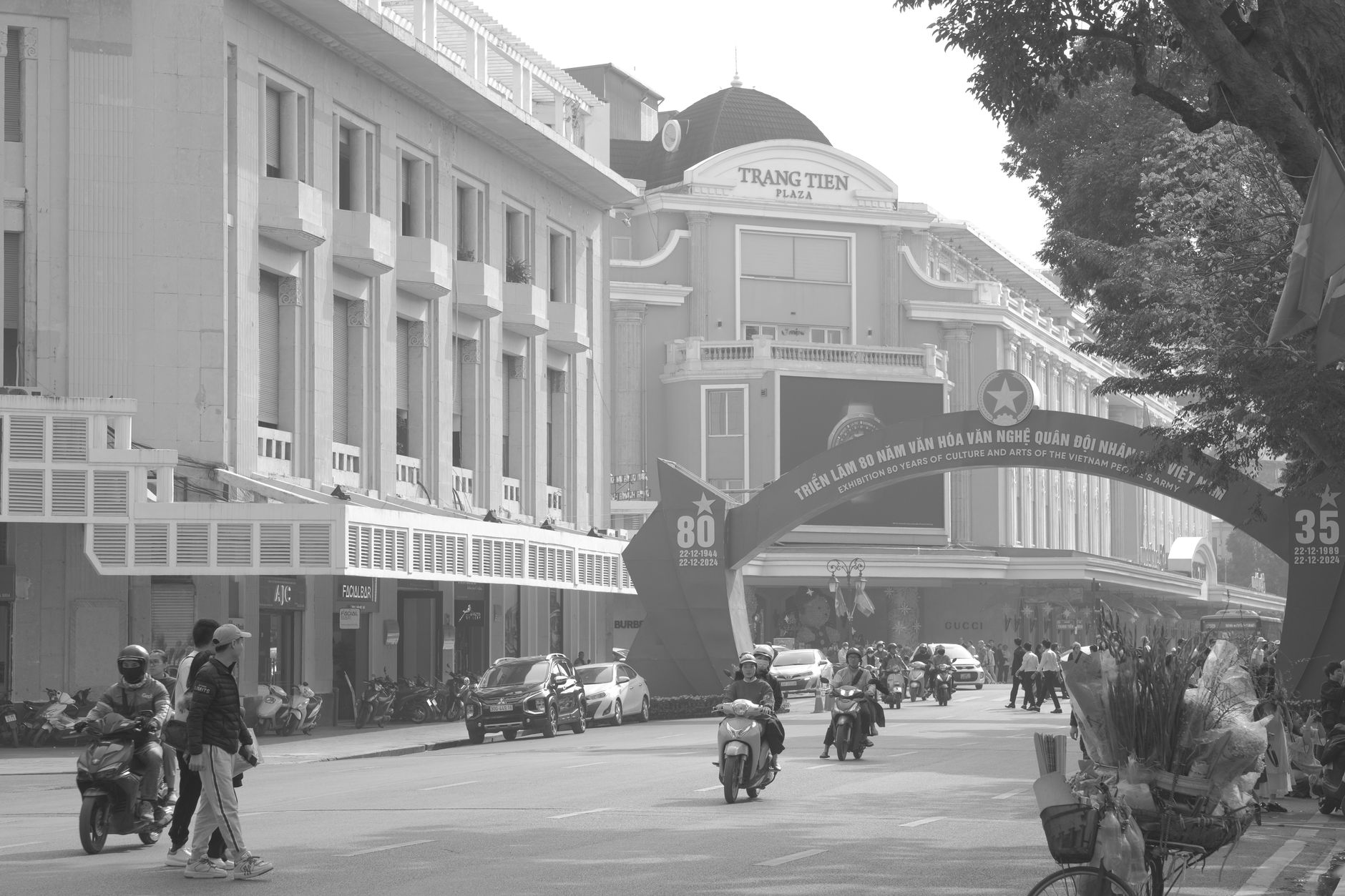 Imagen en blanco y negro de una concurrida escena callejera frente a Trang Tien Plaza.