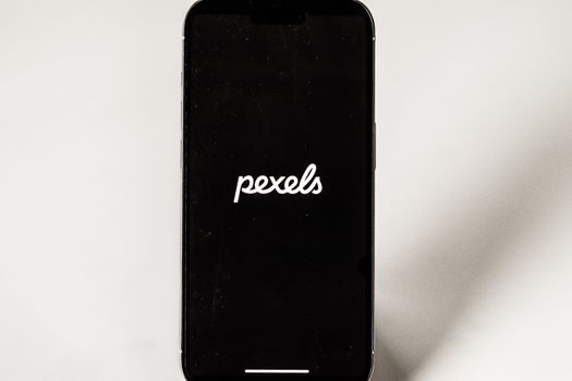 Close-up of an iPhone featuring the Pexels logo, set against a minimal background.