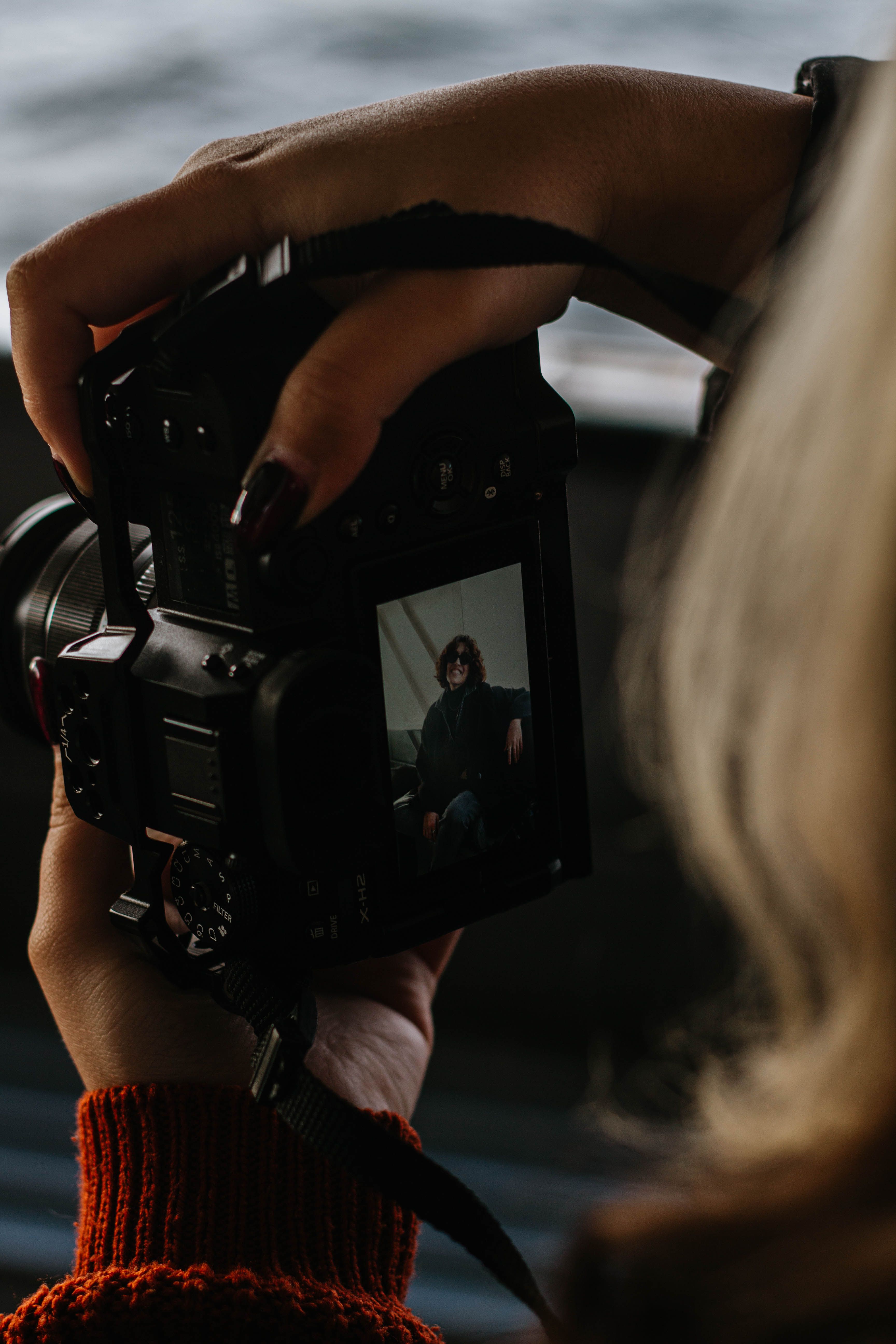 Close-up of a person photographing a portrait, focusing on hands and camera display.