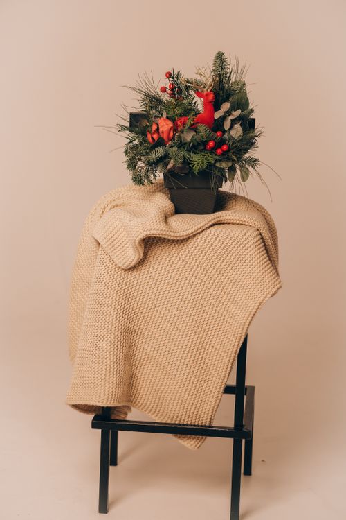 Free Elegant holiday floral arrangement atop a cozy beige knit throw. Stock Photo