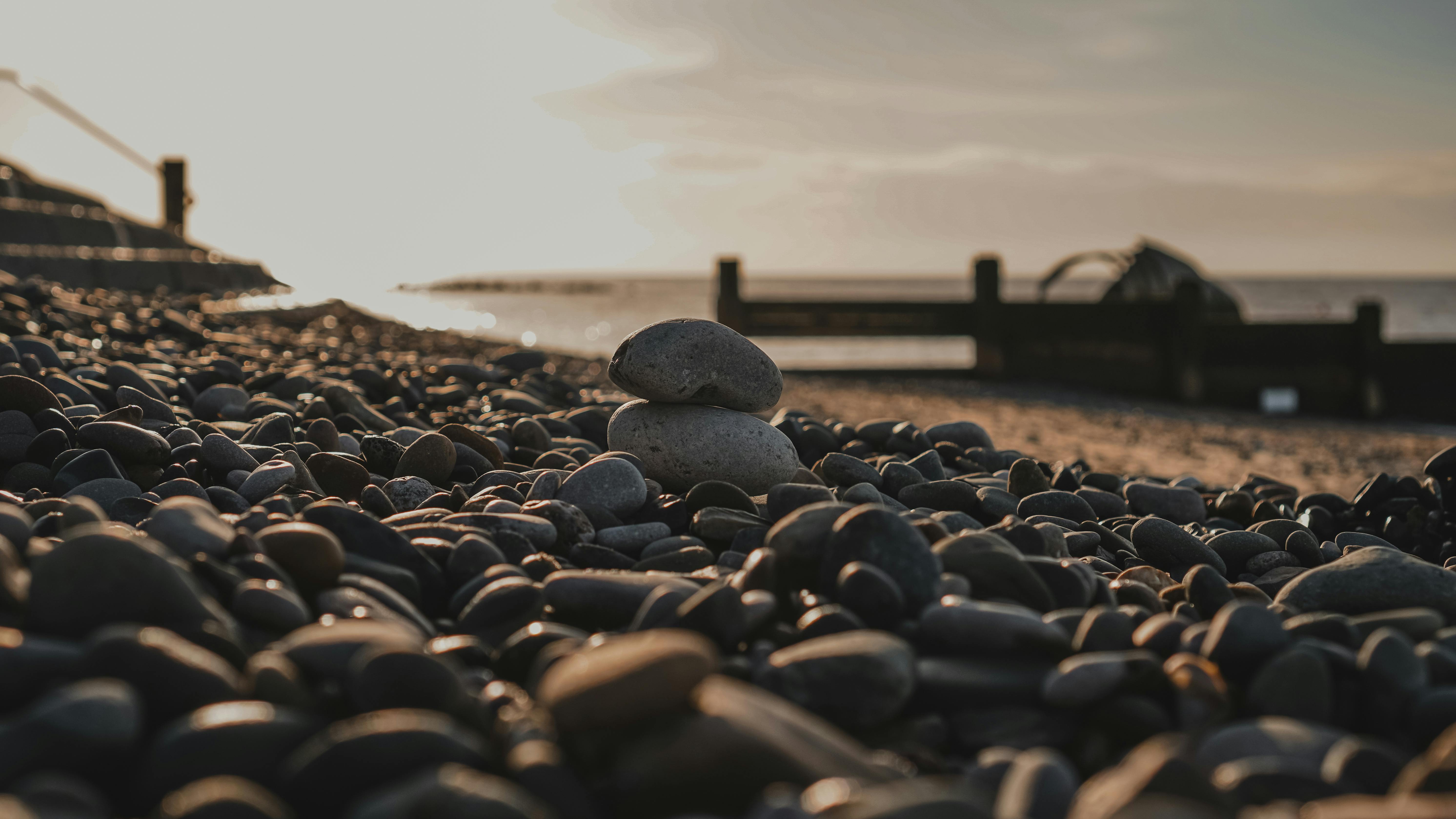 Serene pebble beach with stacked stones at sunrise, epitomizing calm and balance.