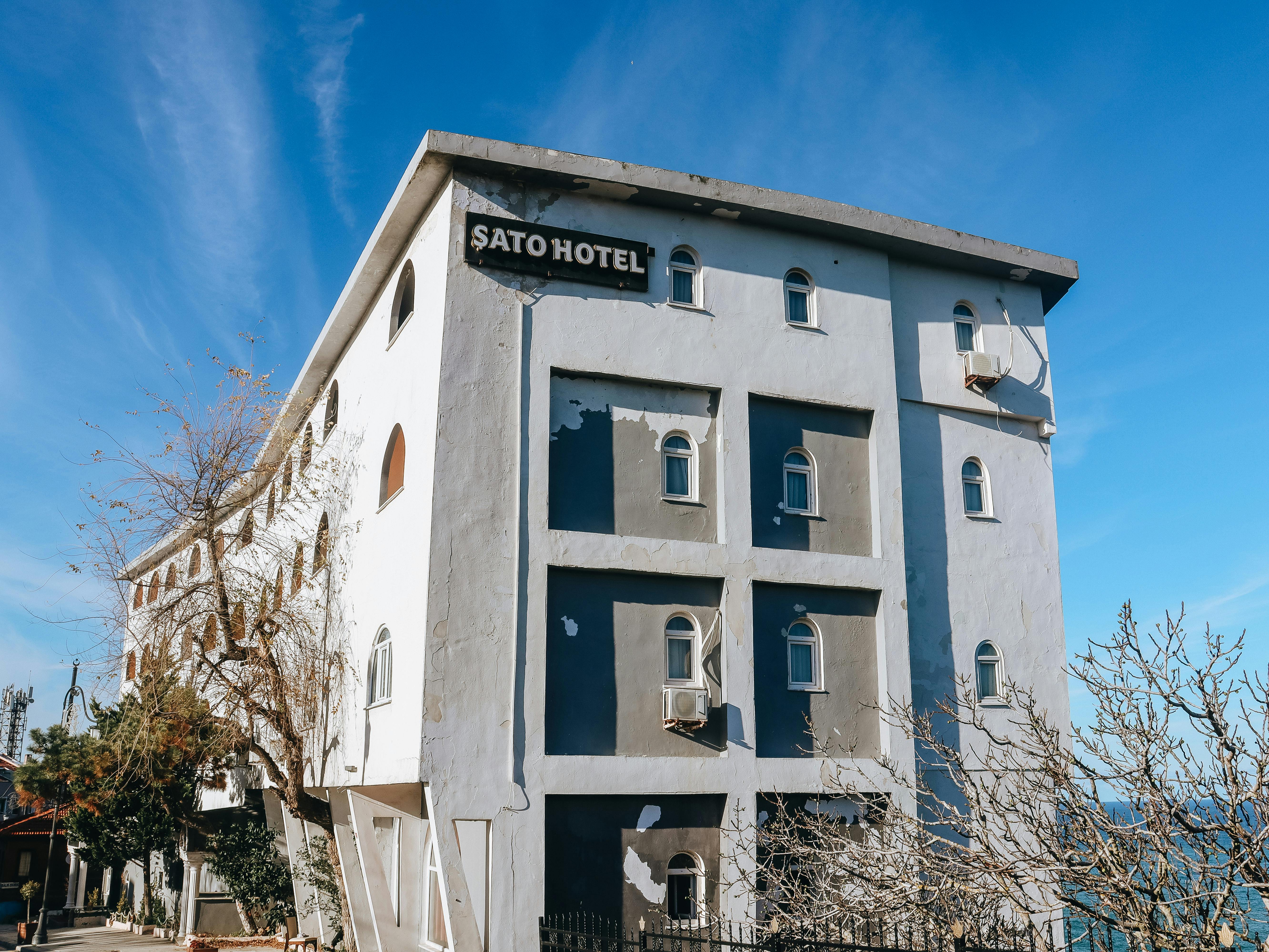 Sato Hotel building with peeling paint under a bright blue sky, showcasing urban architecture.