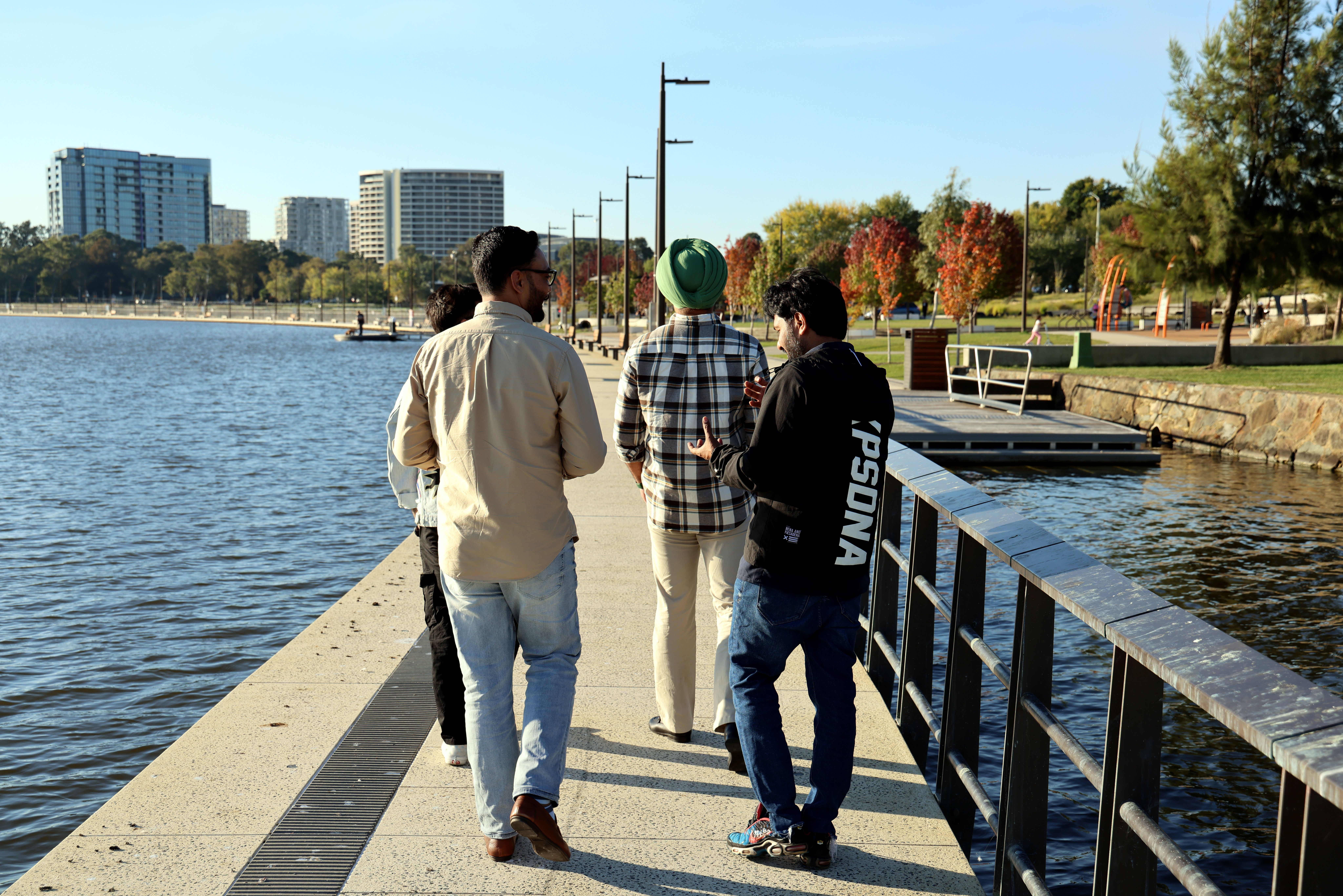 Group Walking on Scenic Waterfront Promenade · Free Stock Photo