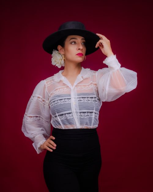 Free Portrait of a woman in traditional Mexican attire with a vibrant red background. Stock Photo