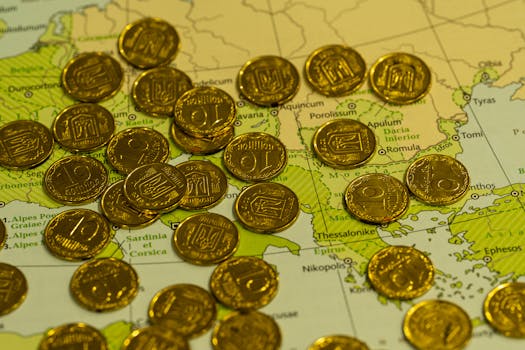 Pile of gold coins placed on top of a detailed geographical map.
