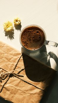 Cozy morning scene with coffee cup and rustic wrapped package. Natural light.