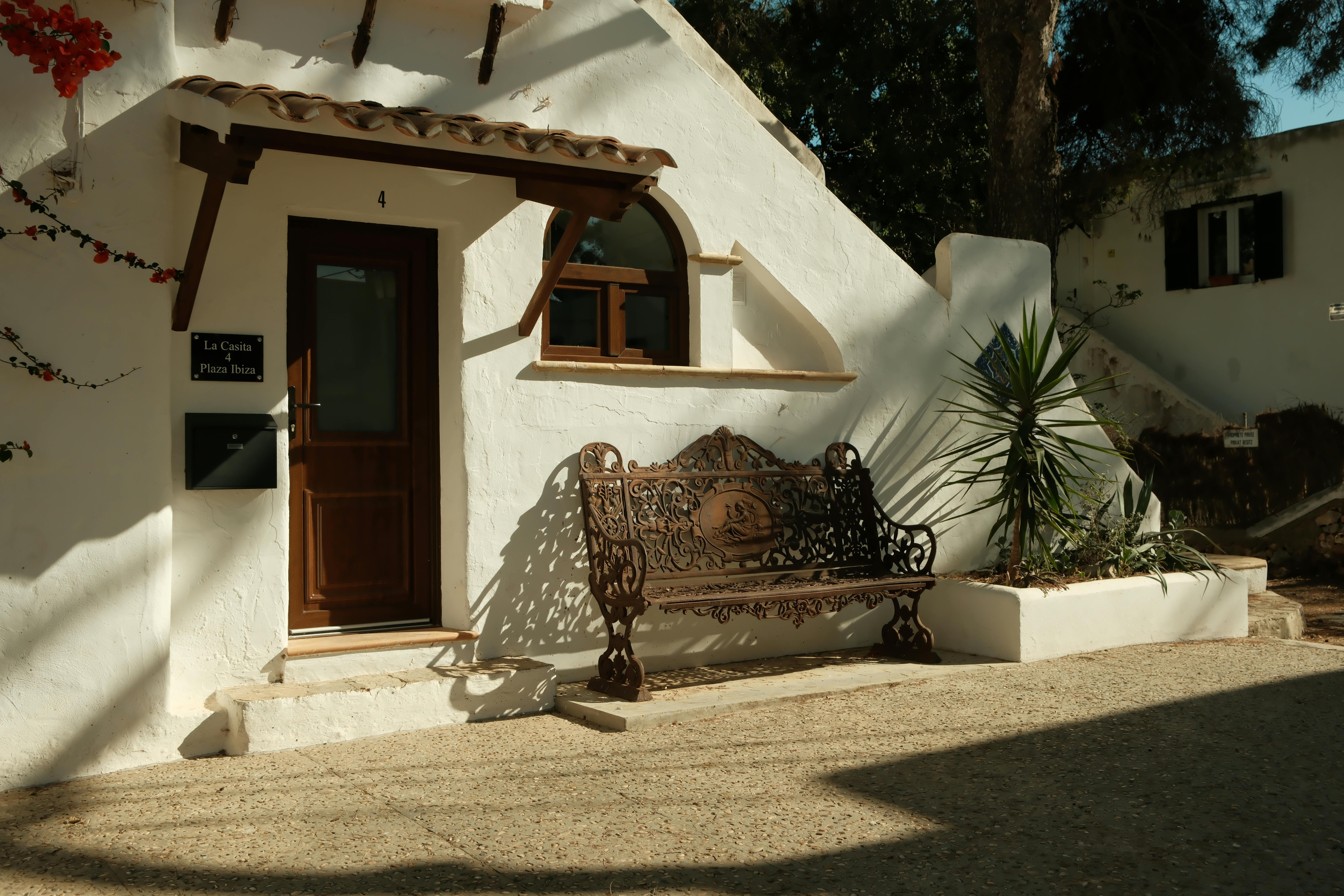 Captivating view of a Mediterranean style villa entrance with iron bench in Cala d'Or, Spain.