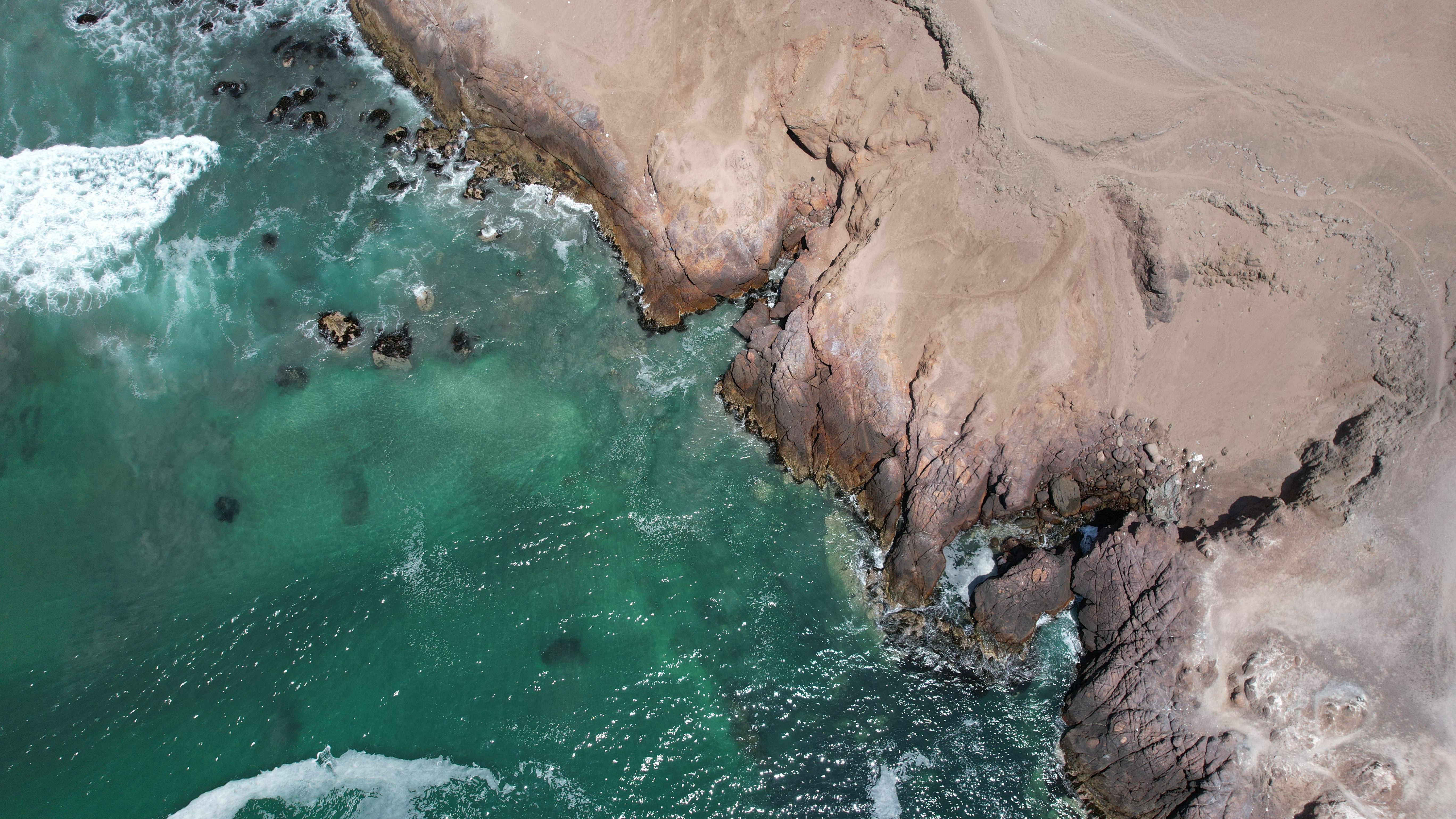 Stunning aerial shot of Chile's rugged coastline with turquoise waters and rocky cliffs.