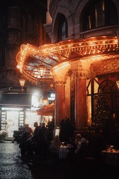 A cozy Istanbul street scene at night, featuring warm lights and lively cafe ambiance.