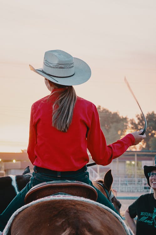 Free Woman Wearing White Cowboy Hat And Red Top Riding On Horse Stock Photo