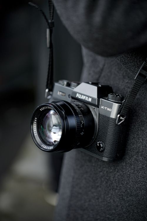 Free Detailed image of a vintage-style camera hanging on a black strap, showcases elegant design. Stock Photo