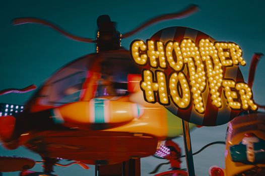 Exciting helicopter-themed carousel ride at an illuminated carnival during nighttime.