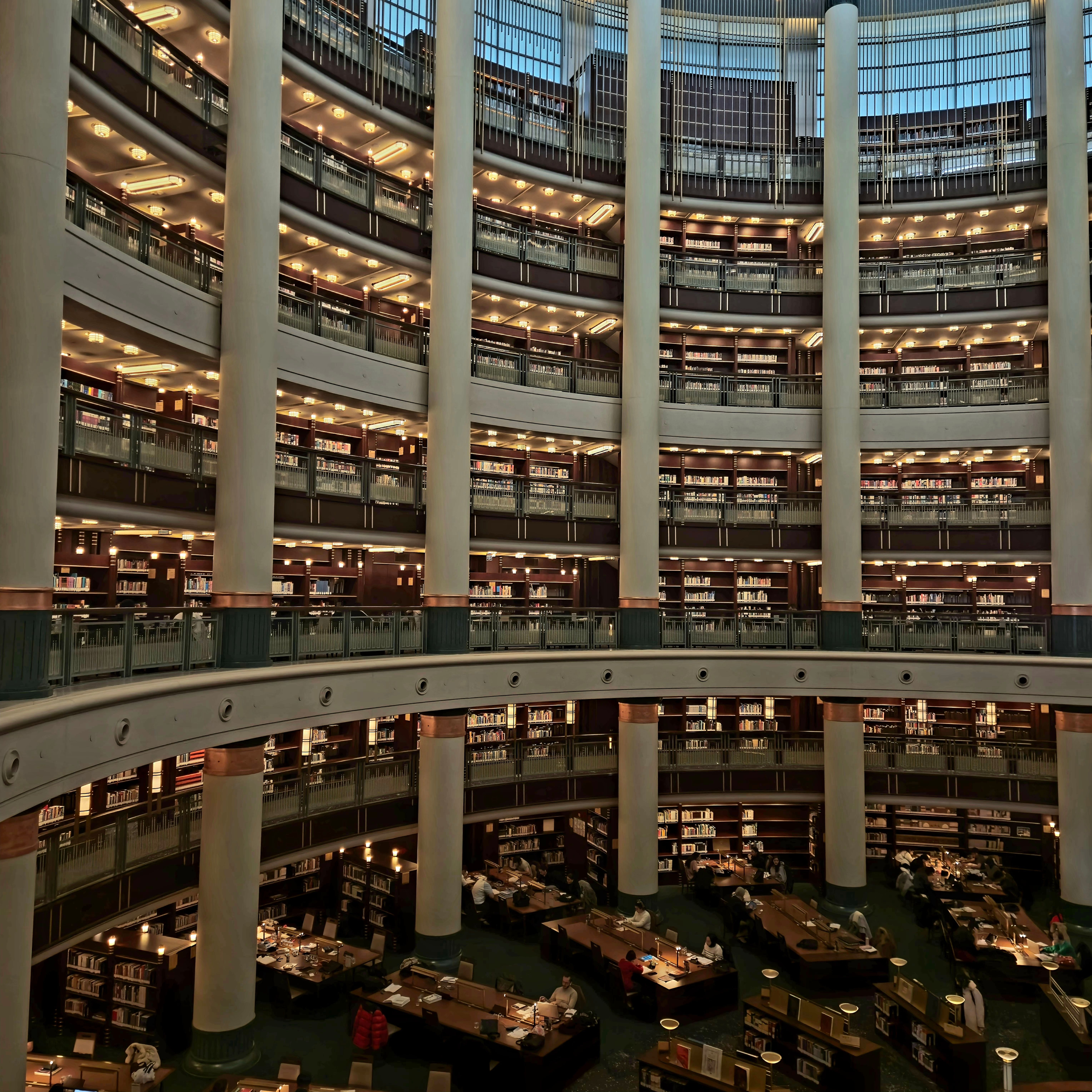 Expansive circular library interior featuring multi-tiered bookshelves and reading tables.