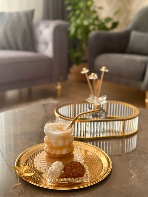 Free Luxurious coffee presentation with dessert on a gold tray in a stylish living room setting. Stock Photo