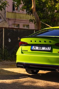 Bright green Skoda Octavia car parked in an urban outdoor setting with sunlight.