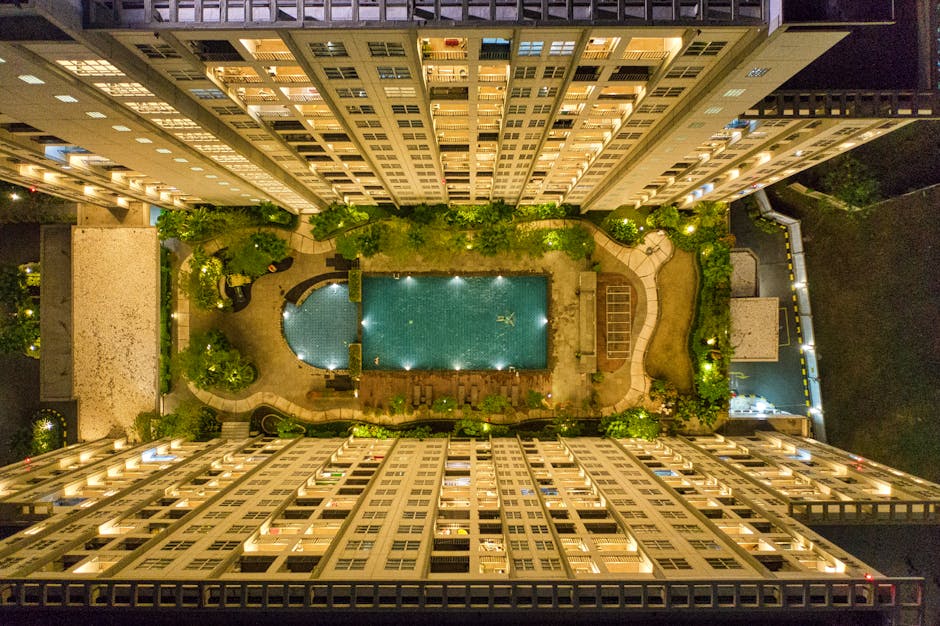 High-angle Photography of Rectangular Green Swimming Pool in Between High-rise Buildings