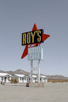 晴朗的天空下，标志性的罗伊汽车旅馆招牌矗立在一片荒芜的风景中