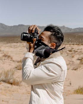 年轻人穿着休闲装在沙漠中用相机拍照