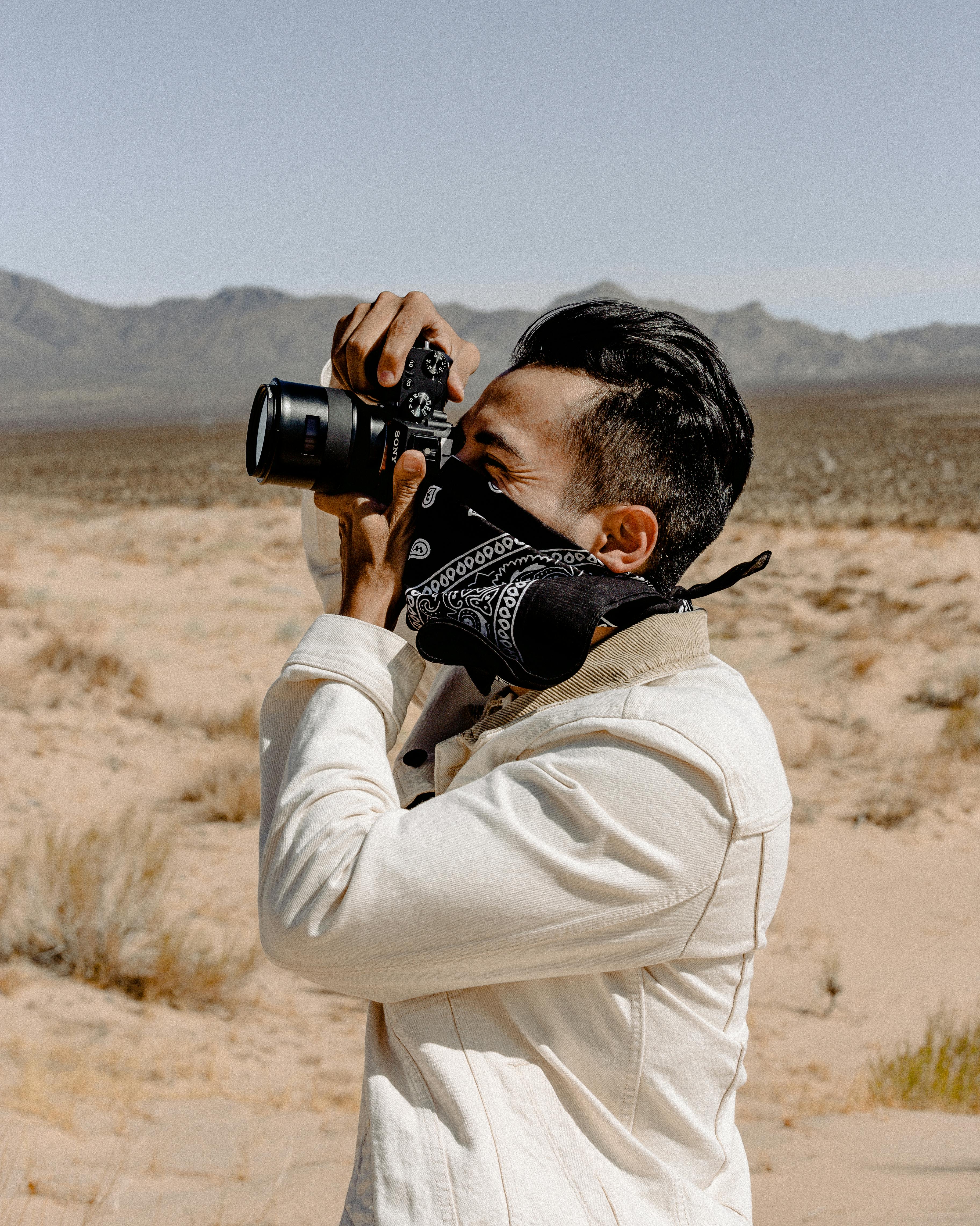 Man Wearing White Denim Jacket Holding Dslr Camera Free Stock Photo