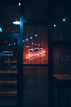 Vibrant neon sign of a churro shop in Rosario at night, creating a moody urban ambiance.