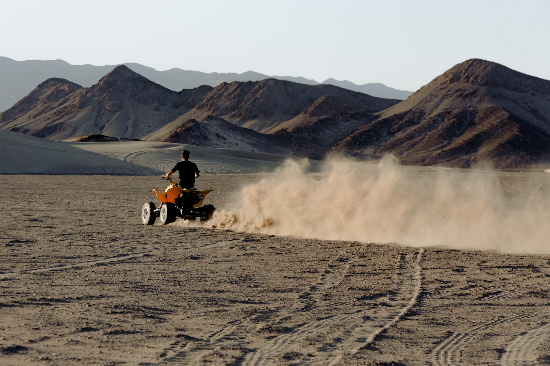 A thrilling ride on an ATV creating dust trails in a vast desert landscape.