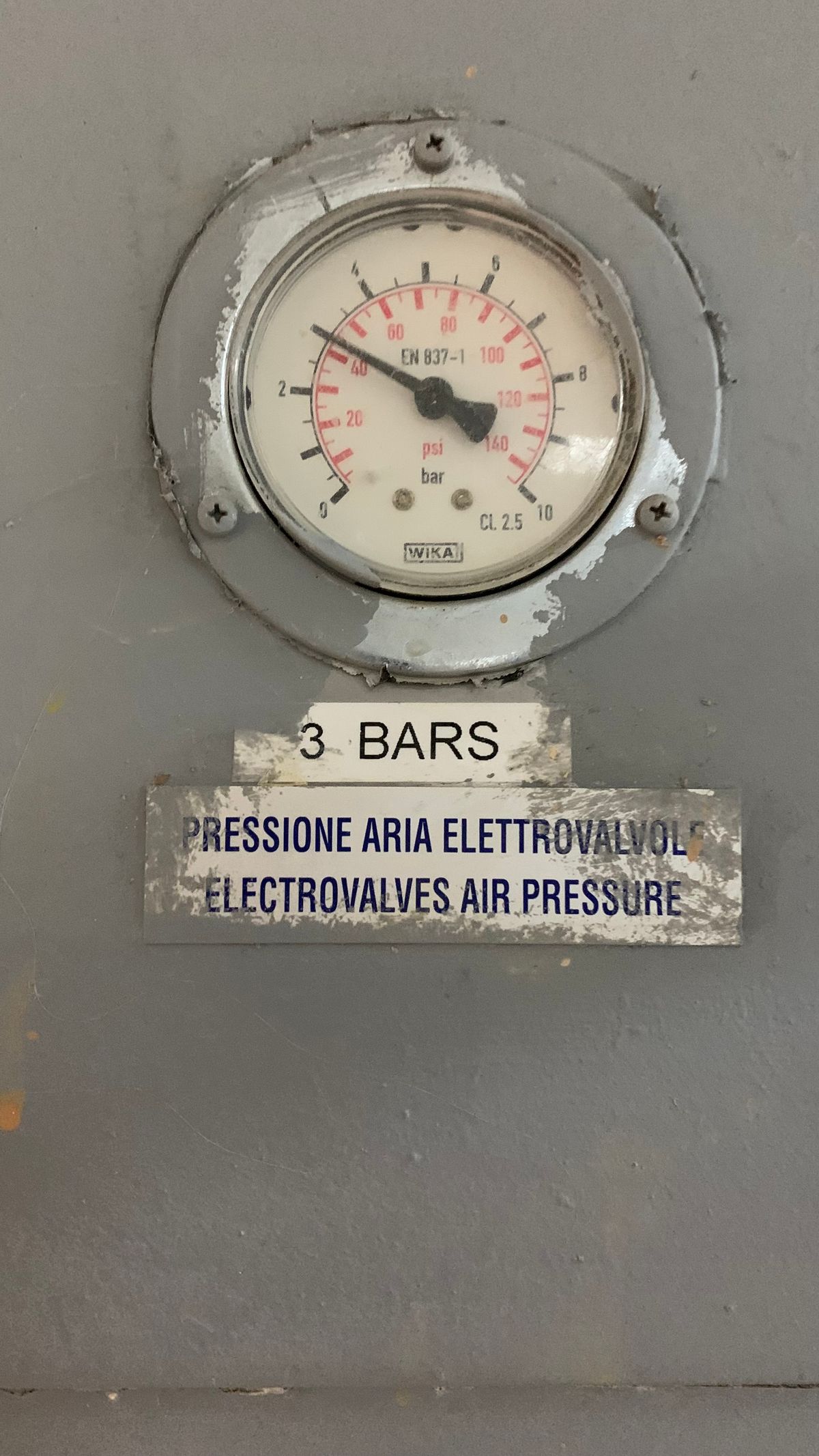 Pressure gauge on industrial piping reading three bar