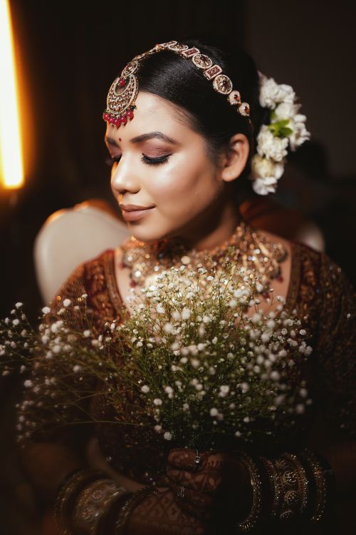 Free Stunning portrait of an Indian bride in traditional attire holding baby's breath flowers. Stock Photo