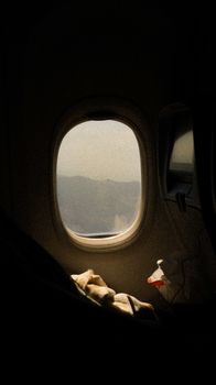 Airplane window view showcasing scenic mountains at daytime.