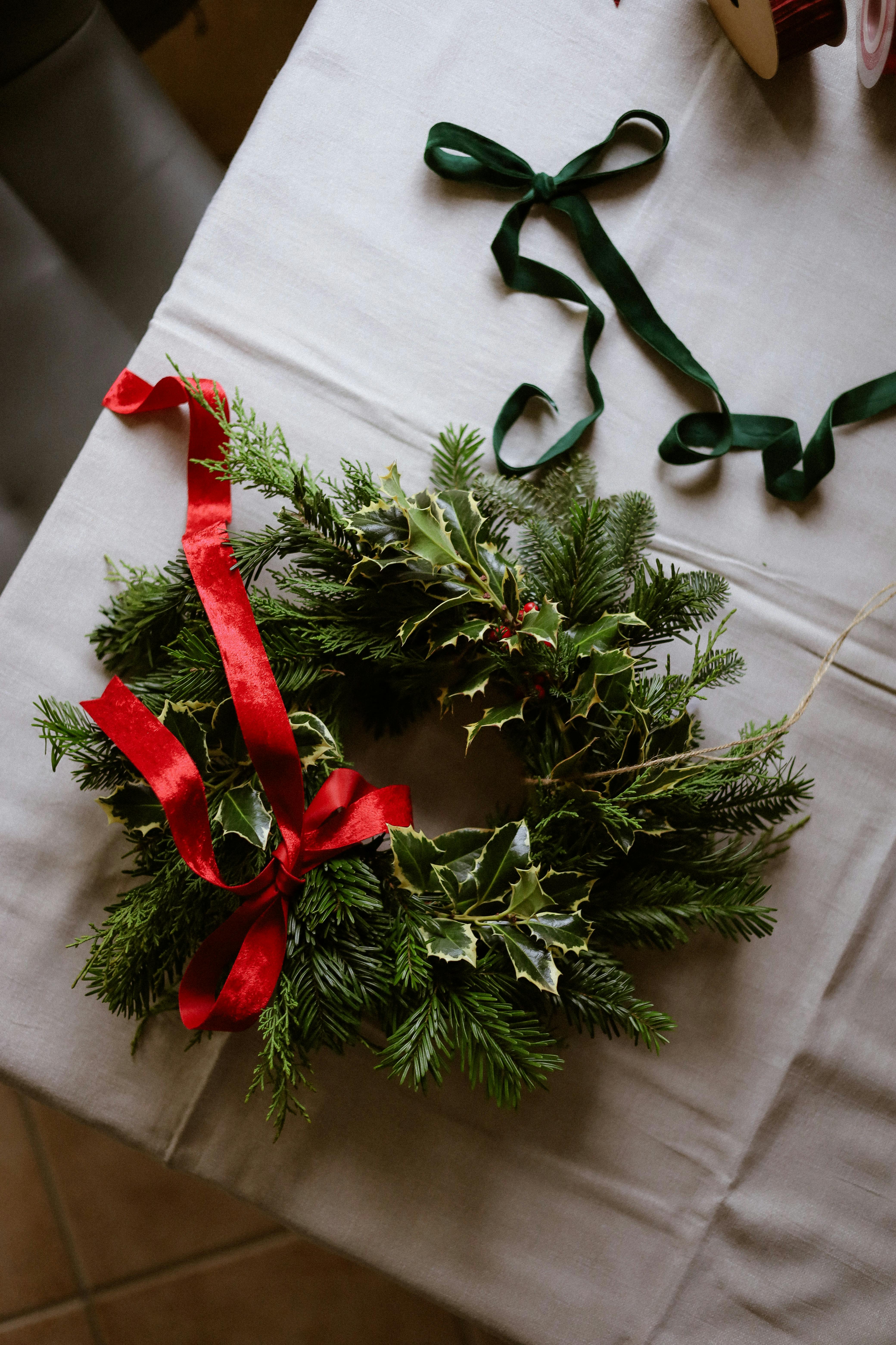 Decorative Christmas wreath with red ribbon on a table.