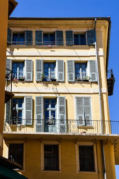 Historic yellow building with blue shutters in Nice, showcasing classic French architecture.