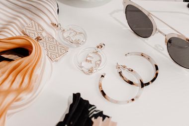 Earrings and sunglasses on a pale surface, photo by Harper Sunday on Pexels