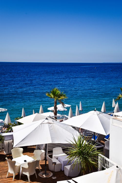 Free Beautiful seaside view on the French Riviera with white umbrellas and deep blue sea under a clear sky. Stock Photo