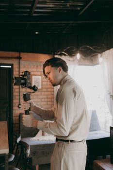 Adult man using a camera stabilizer indoors for smooth video capture.
