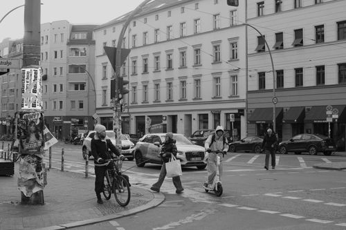Free Dynamic street scene in Berlin with people commuting by bike, scooter, and walking, captured in black and white. Stock Photo
