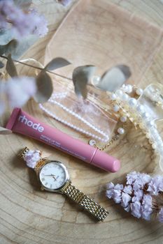 Elegant flat lay featuring cosmetics, a gold watch, and dried flowers for a chic aesthetic