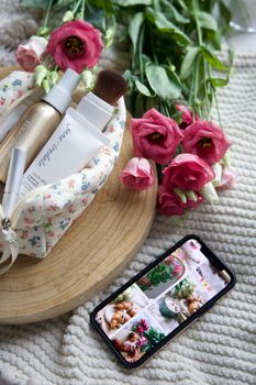 Elegant flat lay of beauty products and roses on cozy fabric surface.
