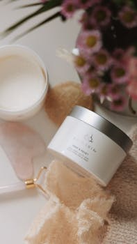 Flat lay of spa essentials including cream, jade roller, and flowers.