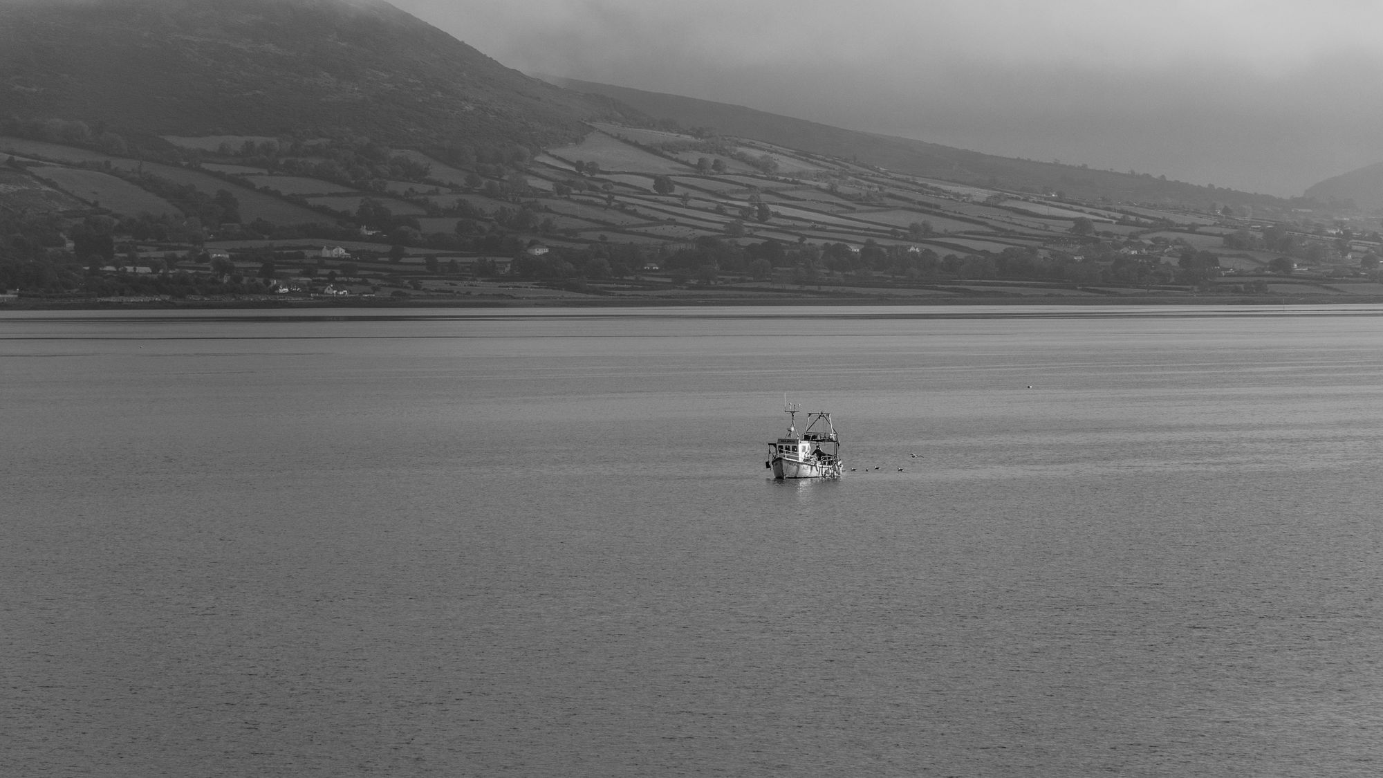 Fishing boat in calm waters of Carlingford Lough, Ireland on a misty day.