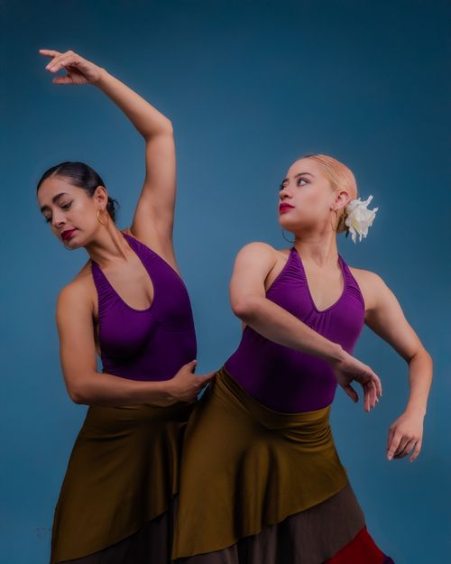 Free Two elegant dancers in vibrant outfits gracefully performing against a blue backdrop. Stock Photo