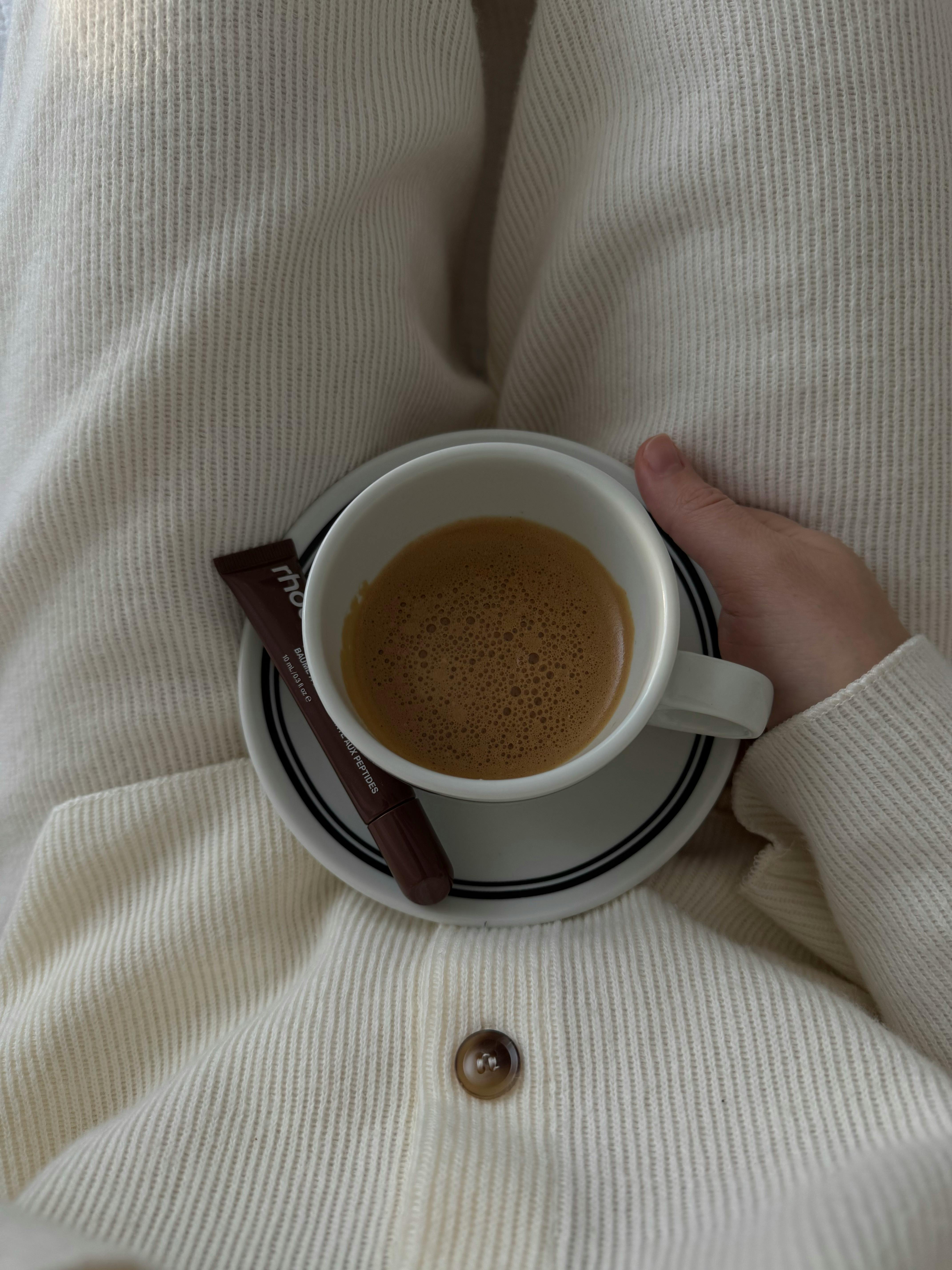 A warm cup of coffee cradled in hand, paired with a chocolate wrapper.