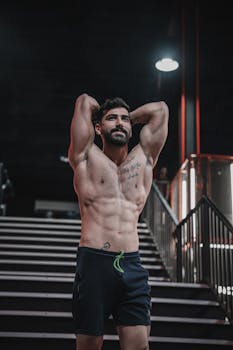 Muscular man posing in gym environment, showcasing fitness and strength.