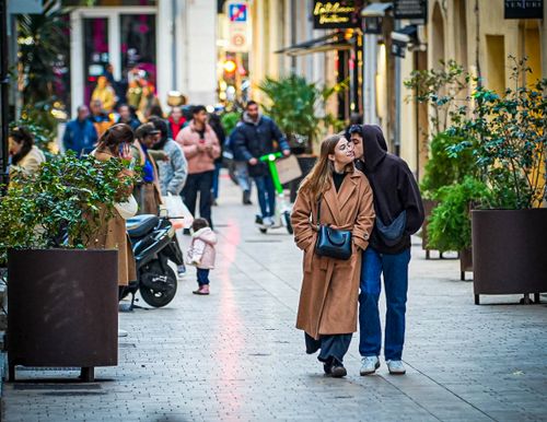 Free Couple walking affectionately in a bustling Marseille street. Capturing city life and love. Stock Photo