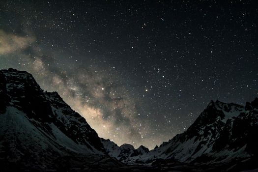 雪山上，满天的繁星映衬出壮丽的景色，捕捉了夜晚大自然的宁静之美