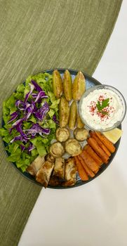 Healthy Mediterranean platter with vegetables, chicken, and creamy dip.