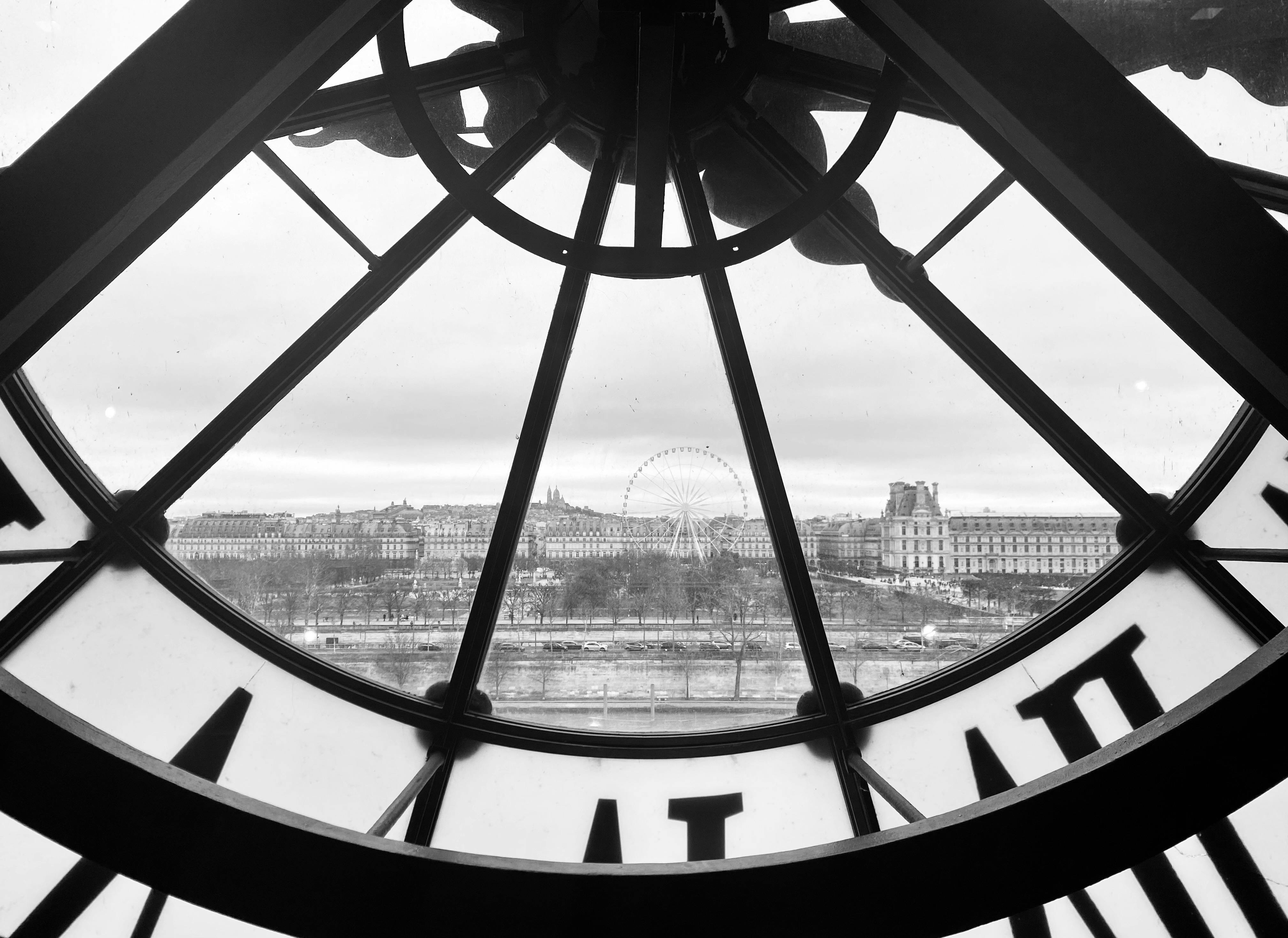 Black and white view from Musée d'Orsay clock overlooking Parisian landmarks.